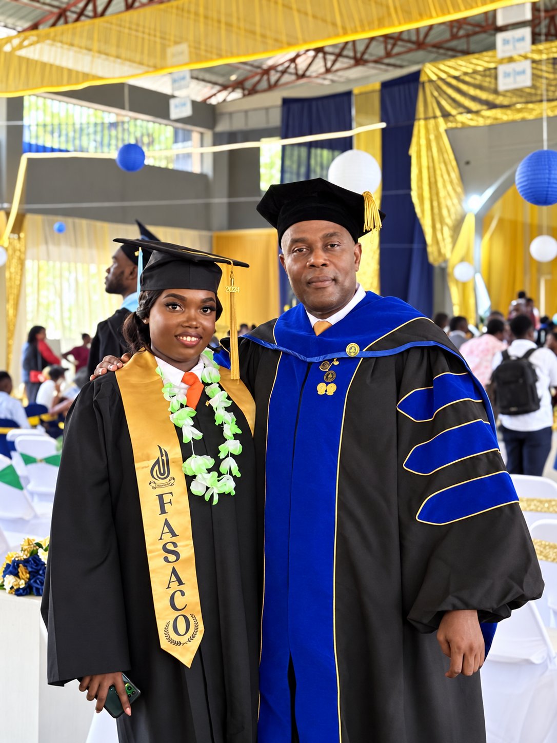 Le Dr Amstrong Jean Charles en toge doctorale lors de la 62e collation des grades de l'UNAH, aux côtés d'une diplômée.