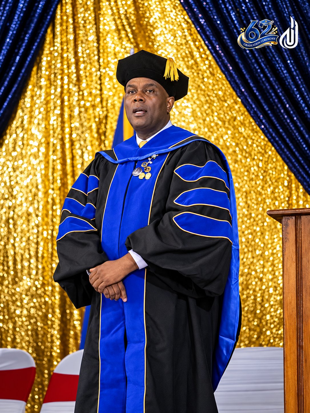 Le Dr Amstrong Jean Charles en toge doctorale devant le drapé de la 62e cérémonie de l'UNAH.